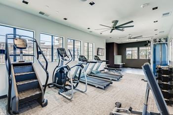 A gym with cardio equipment and windows in a building